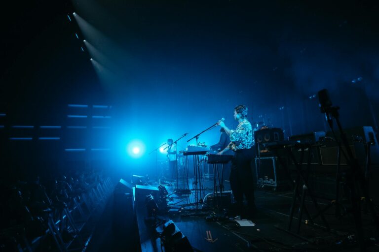 Energetic live band performance on stage with vibrant blue lighting and audience engagement.